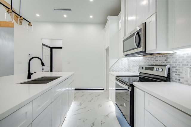 712 Sealy St, Clute, TX 77531 - kitchen with a sink, light countertops, stainless steel appliances, white cabinetry, and decorative backsplash