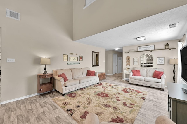 living area featuring baseboards, light wood-type flooring, and visible vents