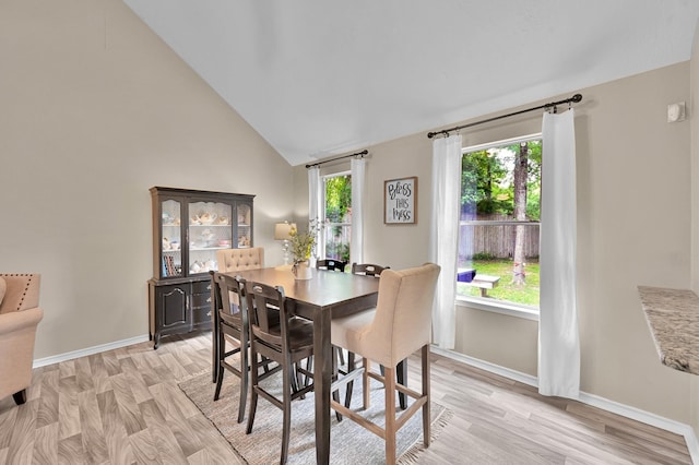 dining space featuring baseboards, vaulted ceiling, and light wood finished floors