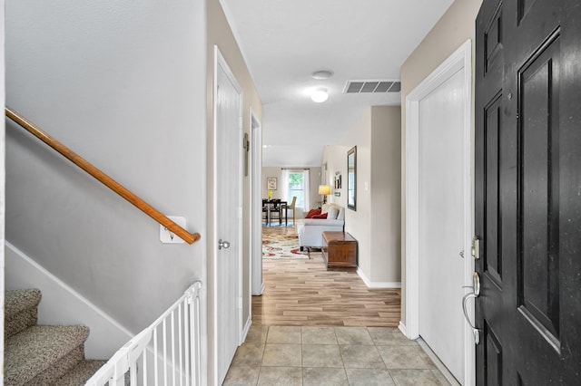 interior space with visible vents, baseboards, light tile patterned floors, and stairway