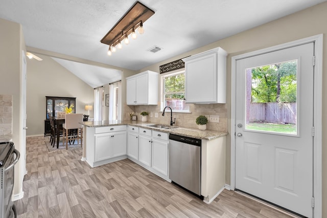 kitchen featuring stainless steel dishwasher, lofted ceiling, light stone countertops, white cabinets, and a sink