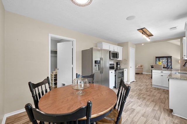 dining room featuring baseboards, light wood finished floors, and visible vents