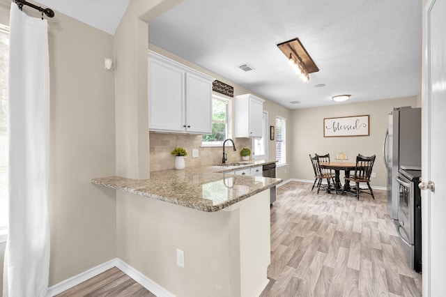 kitchen featuring white cabinets, light stone counters, a sink, electric stove, and light wood-type flooring