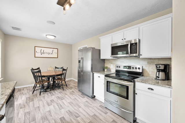 kitchen featuring decorative backsplash, visible vents, appliances with stainless steel finishes, light stone countertops, and white cabinetry