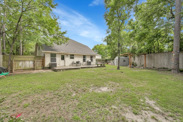 rear view of house featuring a fenced backyard, a shed, an outbuilding, and a deck