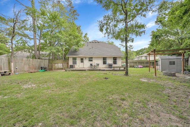 rear view of house featuring a wooden deck, a fenced backyard, a shed, a lawn, and an outbuilding