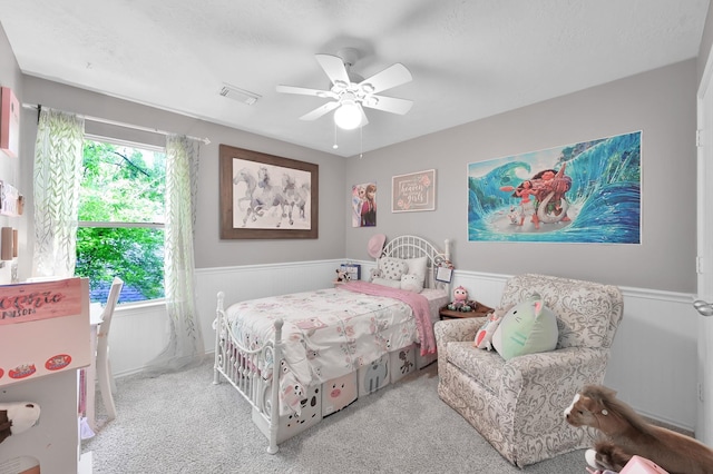 bedroom featuring ceiling fan, visible vents, wainscoting, and carpet