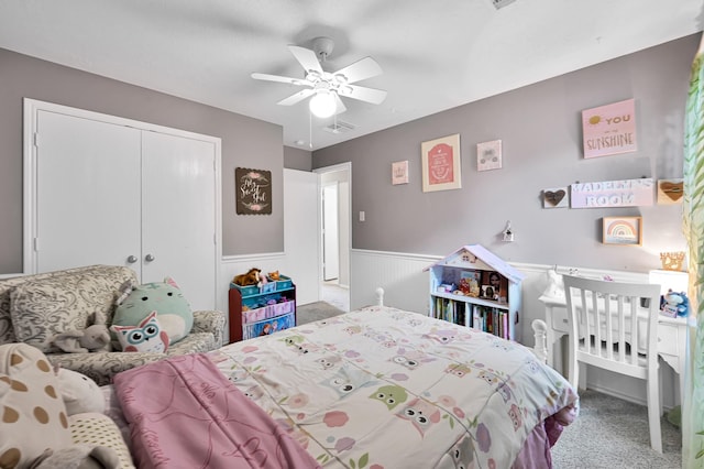 bedroom featuring carpet floors, visible vents, wainscoting, a closet, and a ceiling fan