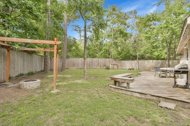 view of yard with a fenced backyard, a fire pit, and a wooden deck