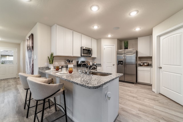kitchen with light wood-style floors, white cabinets, stainless steel appliances, and a peninsula