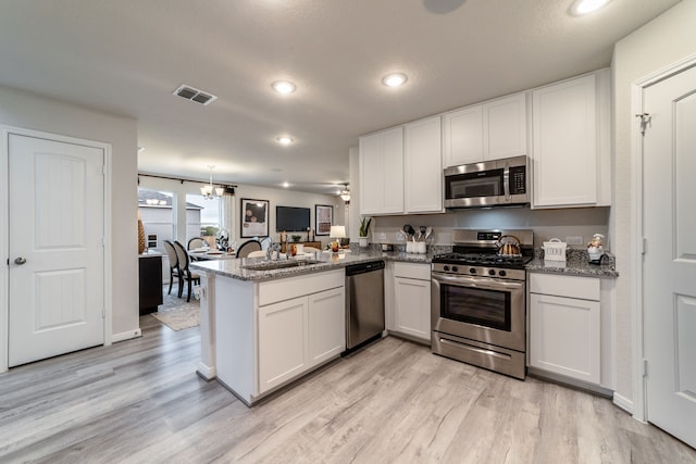 kitchen featuring visible vents, a sink, light wood-style flooring, and stainless steel appliances