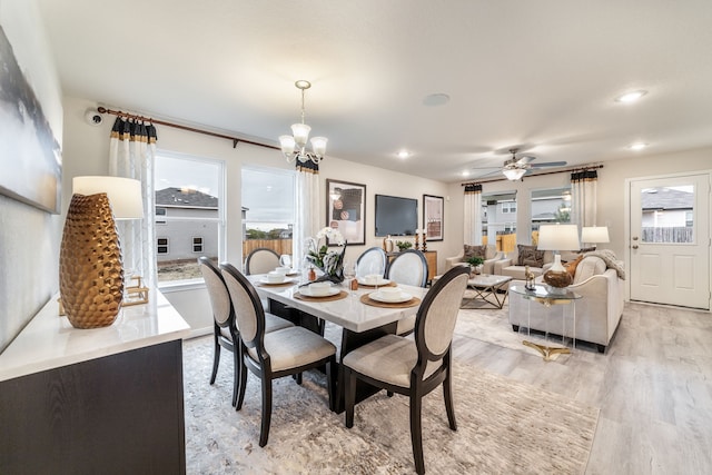 dining space with light wood-style floors, ceiling fan with notable chandelier, and recessed lighting