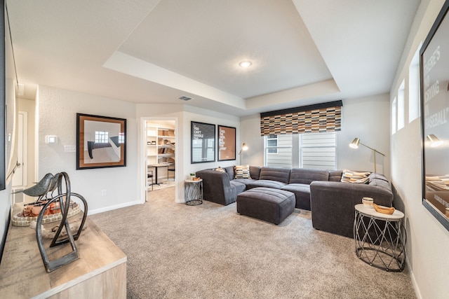 carpeted living area featuring a raised ceiling, baseboards, a wealth of natural light, and visible vents