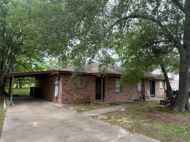 single story home featuring covered porch, brick siding, driveway, and a carport