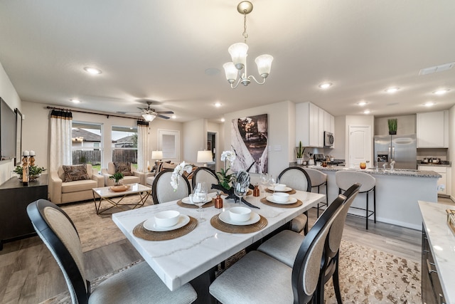 dining area with recessed lighting, light wood-style flooring, ceiling fan with notable chandelier, and visible vents