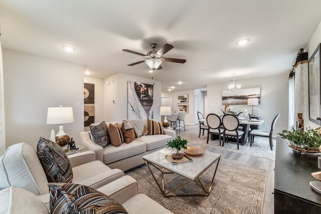 living area with recessed lighting, baseboards, ceiling fan with notable chandelier, and light wood-type flooring
