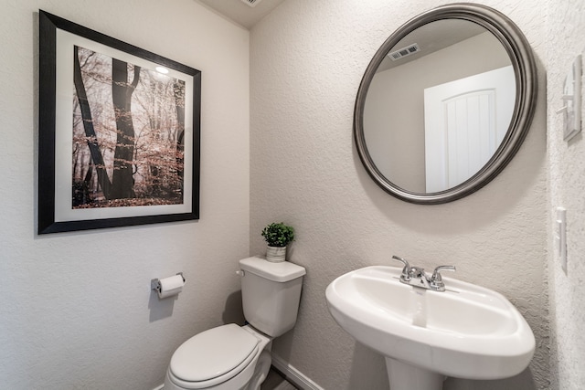 bathroom with a sink, toilet, and visible vents
