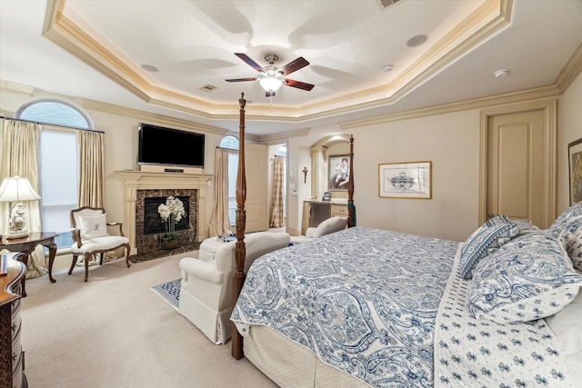 carpeted bedroom with crown molding, a high end fireplace, a raised ceiling, and visible vents