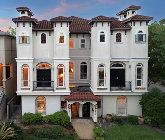 view of front of home with a tile roof, a balcony, and stucco siding