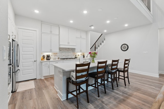 9726 Dani Lake Dr, Tomball, TX 77375 - kitchen with light wood-style flooring, gas stovetop, recessed lighting, light countertops, and a breakfast bar area