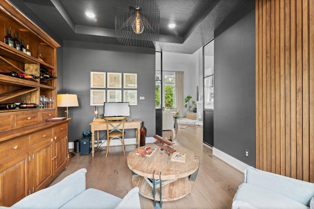 office with baseboards, a tray ceiling, and wood finished floors