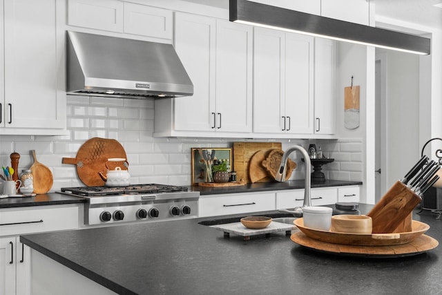 kitchen featuring under cabinet range hood, dark countertops, and white cabinets