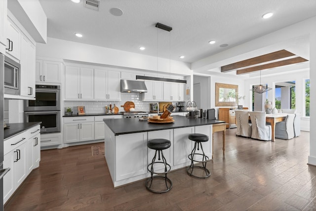 kitchen with appliances with stainless steel finishes, under cabinet range hood, white cabinets, and dark countertops