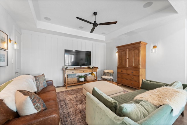living area featuring ceiling fan and a tray ceiling