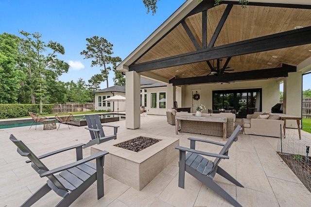 view of patio / terrace with fence, a fenced in pool, a ceiling fan, and an outdoor living space with a fire pit
