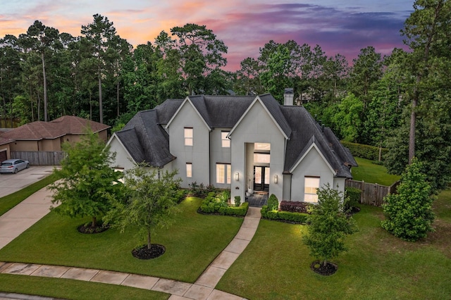 view of front of house featuring a yard, a shingled roof, and stucco siding