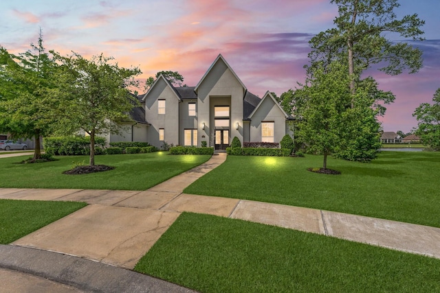 view of front of house featuring a front lawn, stucco siding, and french doors