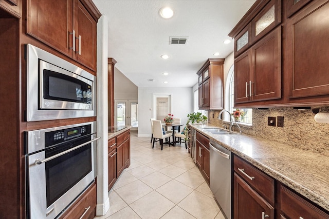 kitchen with light stone countertops, appliances with stainless steel finishes, a sink, and visible vents