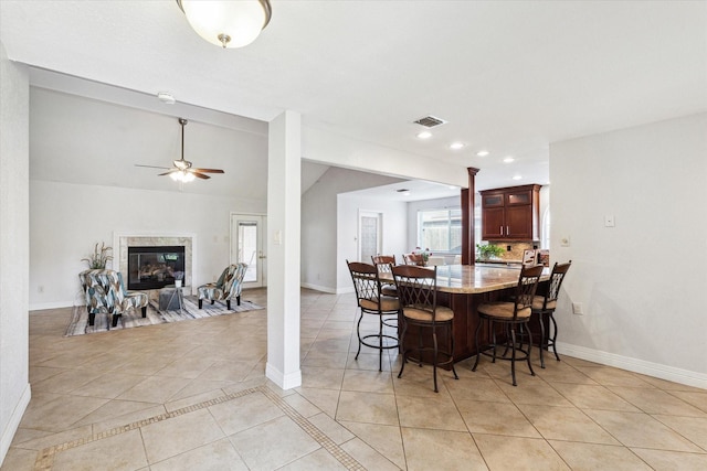 dining room with baseboards, a ceiling fan, decorative columns, and light tile patterned floors