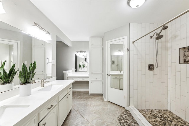 full bathroom featuring double vanity, tiled shower, and a sink