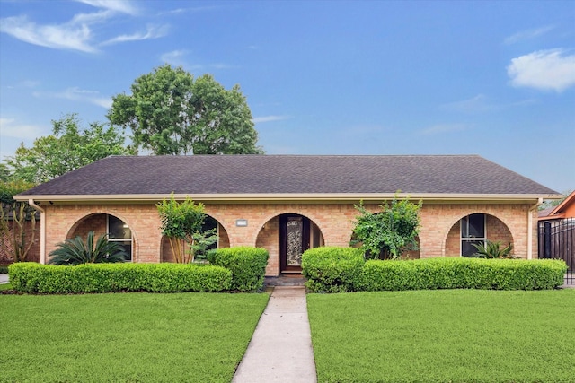 view of front of home with a shingled roof, brick siding, and a front yard