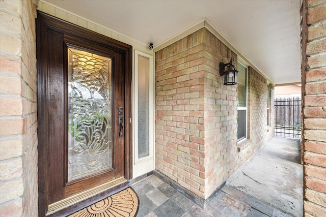 property entrance featuring covered porch and brick siding