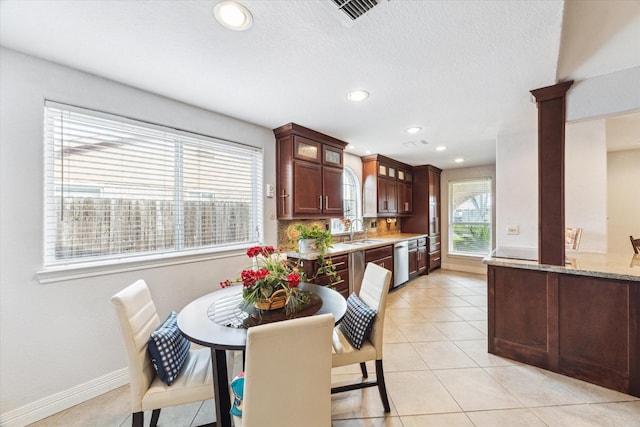kitchen featuring a sink, dishwasher, recessed lighting, baseboards, and glass insert cabinets