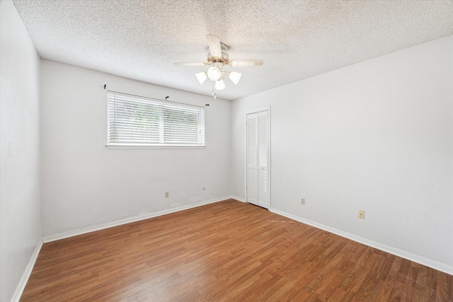 spare room featuring baseboards, a ceiling fan, a textured ceiling, and wood finished floors