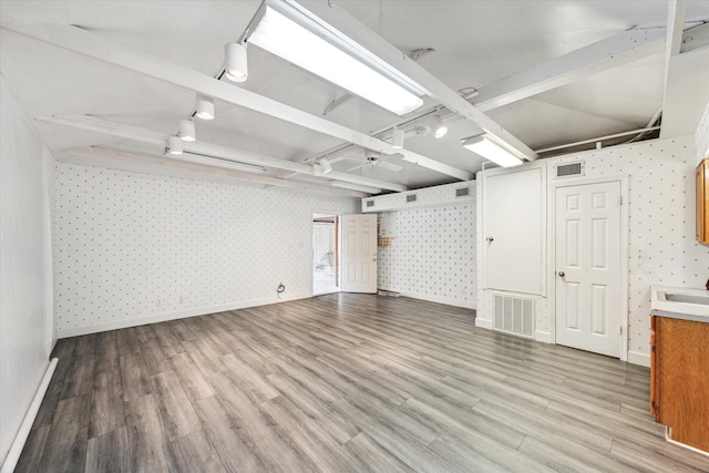 below grade area featuring visible vents, rail lighting, and wallpapered walls
