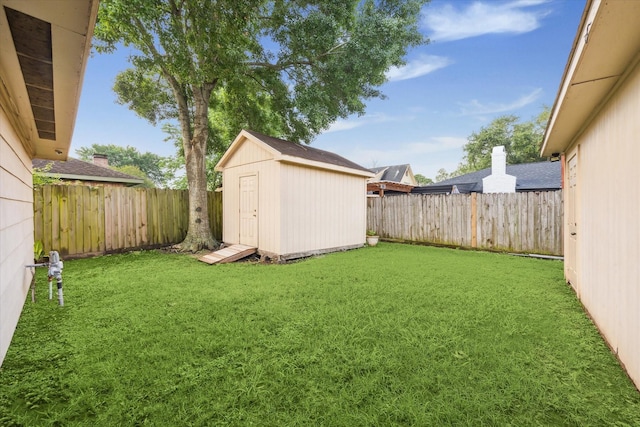 view of yard with a fenced backyard, a storage unit, and an outdoor structure