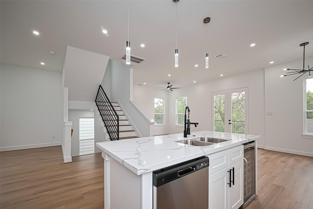 kitchen featuring a sink, stainless steel dishwasher, light wood finished floors, and open floor plan