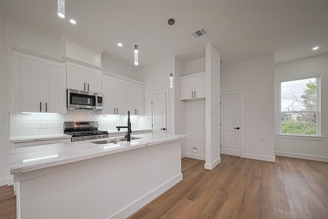 kitchen featuring visible vents, white cabinetry, tasteful backsplash, a sink, and stainless steel appliances