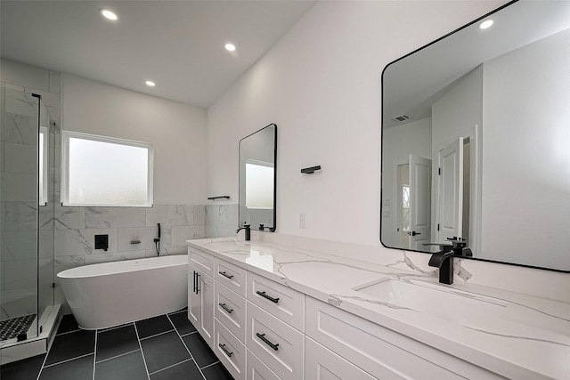 bathroom featuring visible vents, double vanity, a freestanding tub, a shower stall, and a sink
