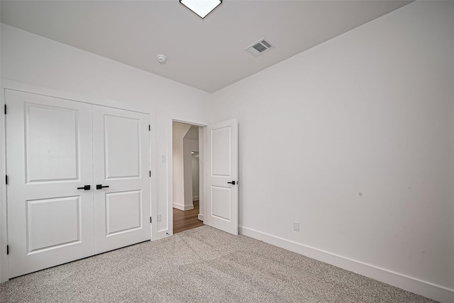 unfurnished bedroom featuring baseboards, visible vents, carpet, and a closet