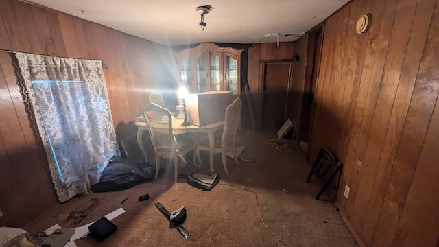 dining area featuring carpet flooring and wood walls