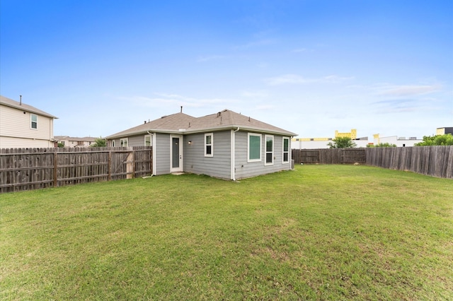 rear view of property with a fenced backyard and a yard