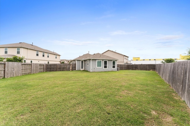 back of house with a yard and a fenced backyard