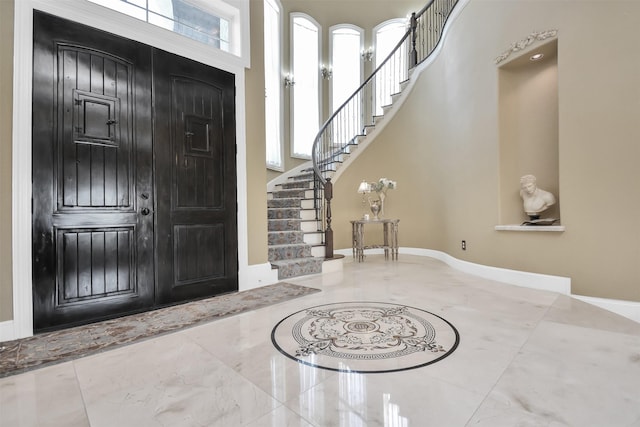 entrance foyer with baseboards, a high ceiling, stairs, and marble finish floor