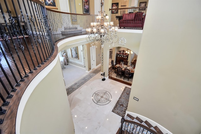 entrance foyer featuring arched walkways, stairway, baseboards, a notable chandelier, and a high ceiling