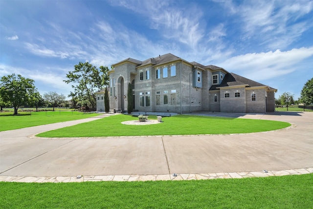 view of front facade featuring curved driveway, a front lawn, and brick siding